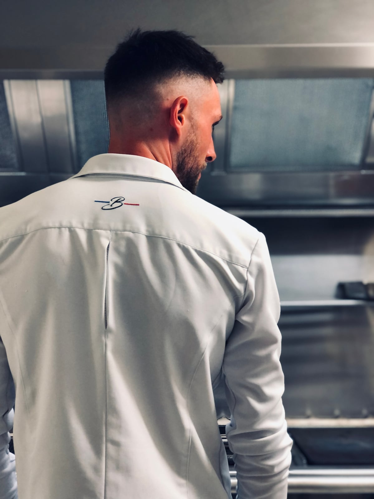 Un chef en veste blanche au travail dans sa cuisine